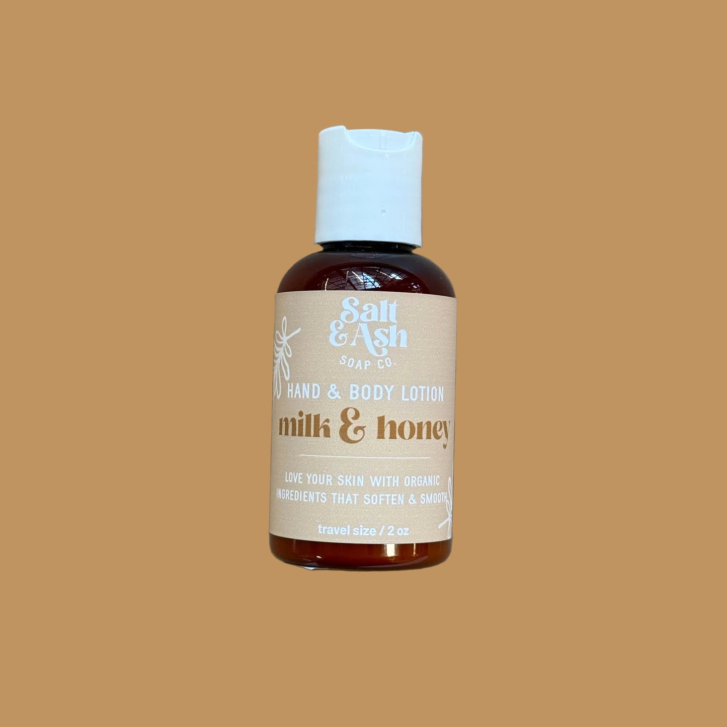 Hand and body lotion bottle labeled 'milk & honey' on a brown background