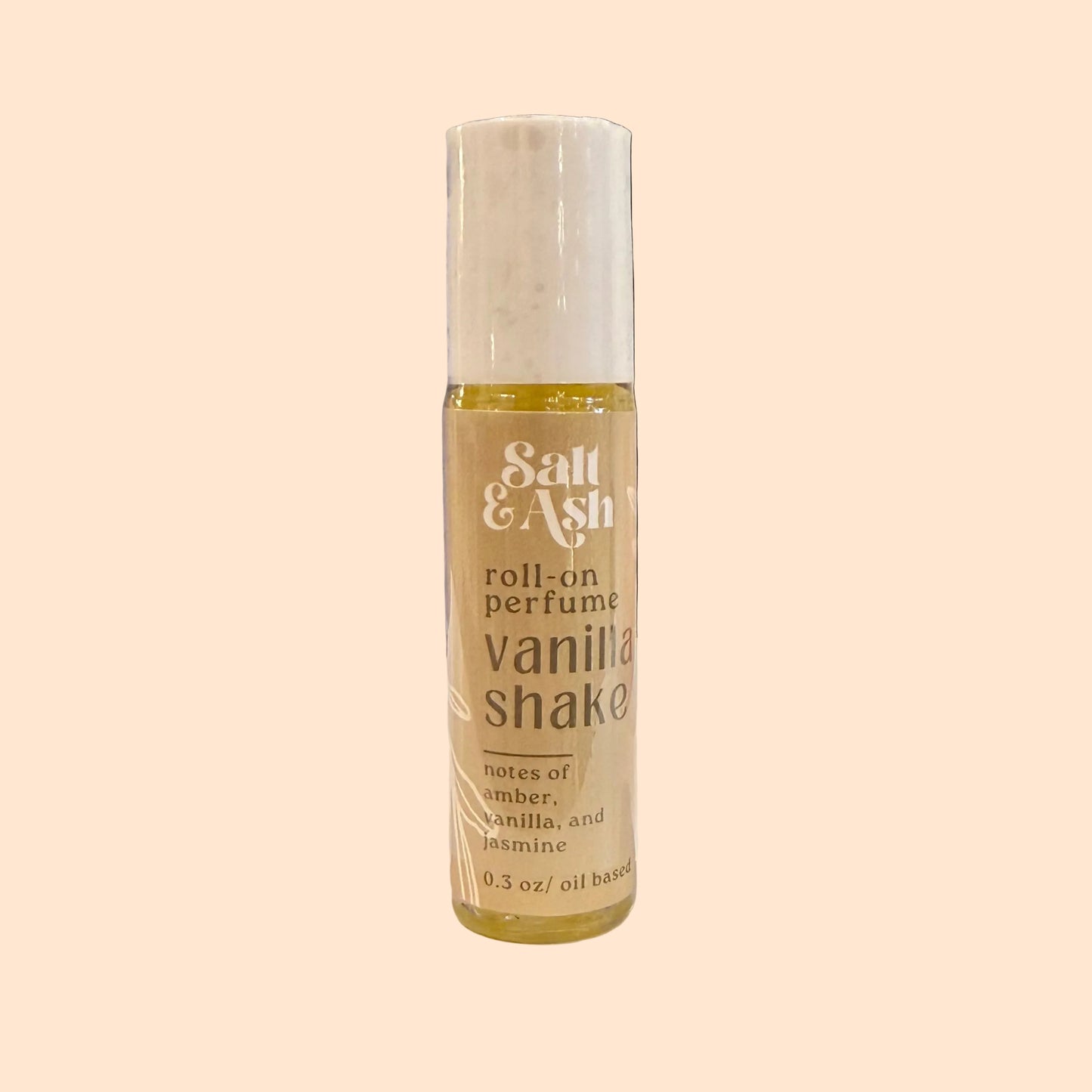Roll-on perfume bottle labeled 'Salt & Ash Vanilla Shake' on a surface with blurred background
