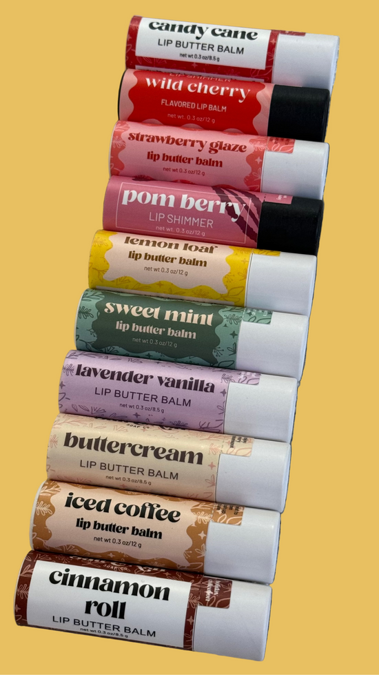 Row of lip balm tubes with various flavors on a textured surface