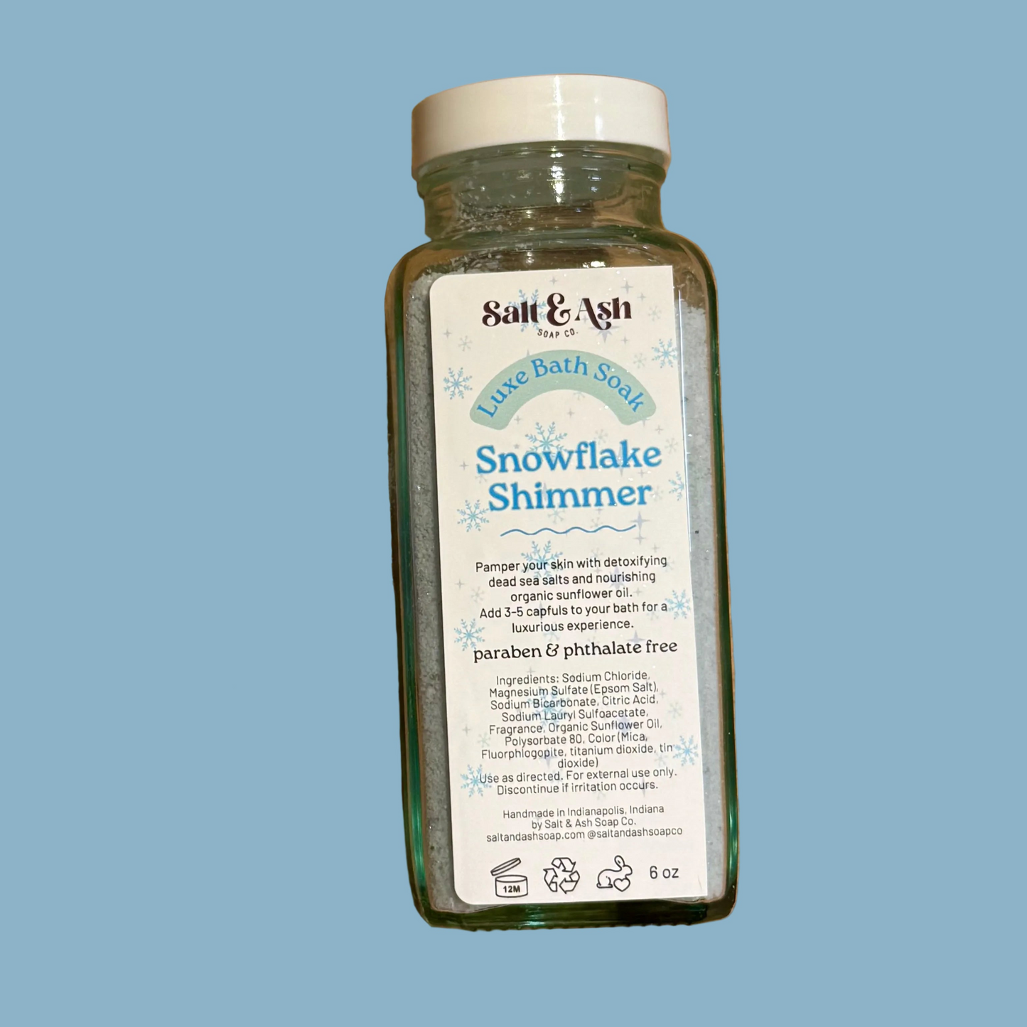 Bottle of Salt & Ash Soap Co Bath Soak Snowflake Shimmer on a blue background