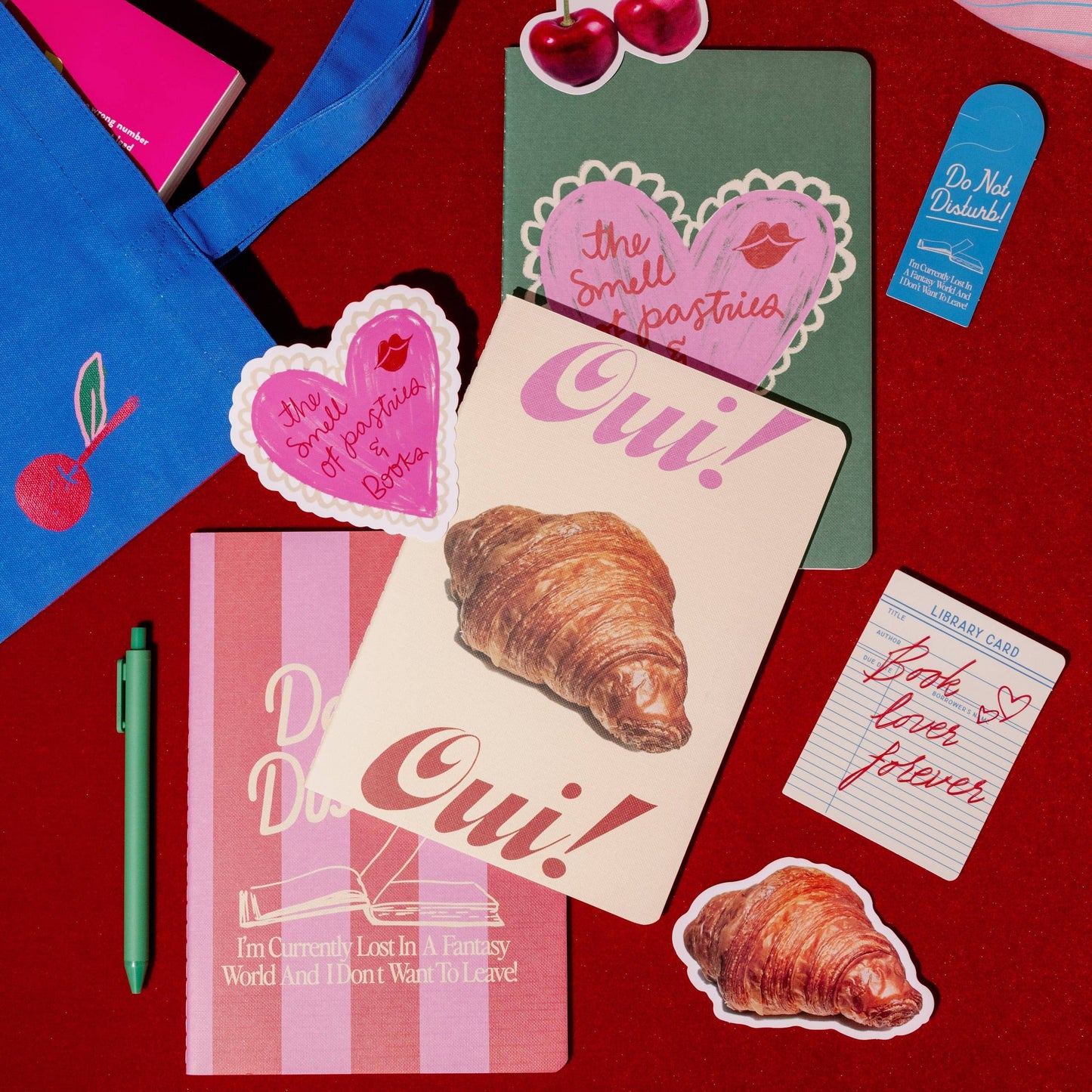 Stationery items including notebooks, stickers, and a pen on a red background