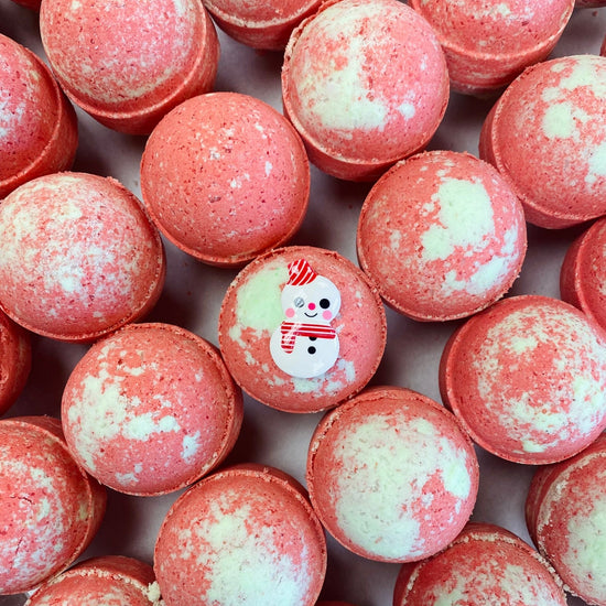 Close-up of red and white bath bombs with a snowman toy on top.