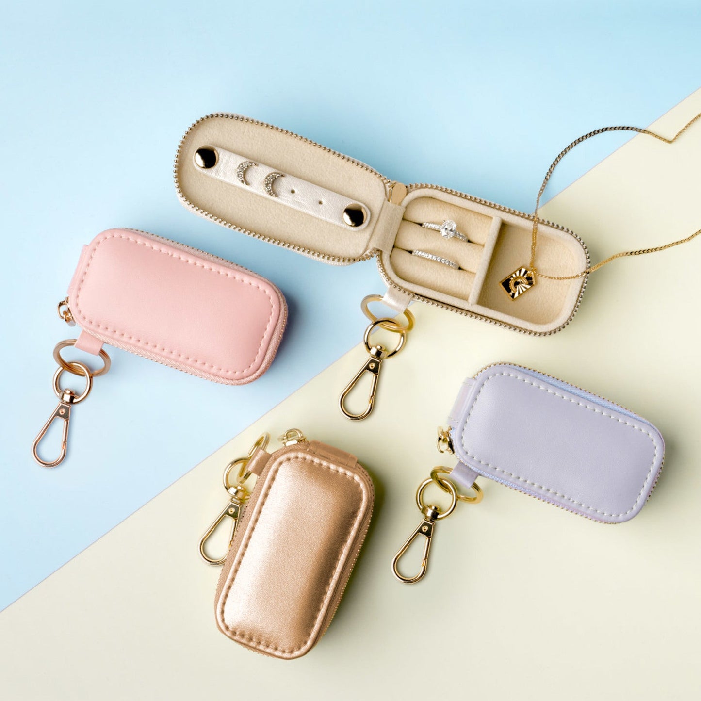 Set of four small leather cases in pink, gold, and blue on a light blue background
