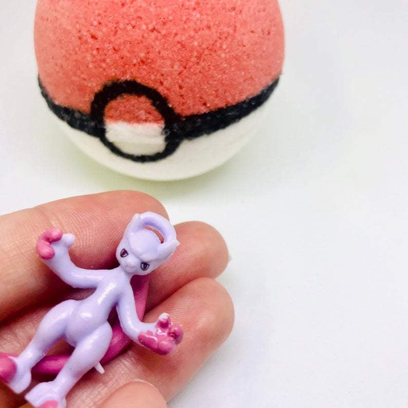 Bath bomb shaped like a Poké Ball held by a hand with a figurine.